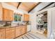 Well-lit kitchen featuring wood cabinets, granite countertops, tiled backsplash, and a view to the dining area at 2837 Reed St, Wheat Ridge, CO 80033