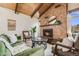 Cozy living room featuring a stone fireplace, wood-beamed ceiling, and stylish furnishings at 2837 Reed St, Wheat Ridge, CO 80033