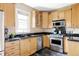 A well-lit kitchen features wood cabinetry, stainless steel appliances, and black countertops at 3365 S Grant St, Englewood, CO 80113