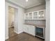 A bar area featuring white cabinets, granite counters, glass shelving, and beverage refrigerator at 4837 S Buchanan St, Aurora, CO 80016