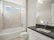 Well-lit bathroom with mosaic tiles, soaking tub, and sleek vanity with black countertop at 4837 S Buchanan St, Aurora, CO 80016