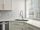 Kitchen sink with stainless steel faucet, quartz countertops and gray tiled backsplash next to a bright window at 4837 S Buchanan St, Aurora, CO 80016