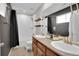 Bright bathroom featuring double sinks, a shower-over-tub and dark accent wall at 16048 Elizabeth St, Thornton, CO 80602