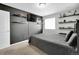 This bedroom features light gray walls, gray carpet, dark accent wall, decorative shelving, and a window at 16048 Elizabeth St, Thornton, CO 80602
