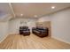Cozy finished basement featuring wood-look floors, an armchair, and a comfortable black leather couch at 1641 Orchard Dr, Denver, CO 80221