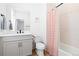 Well-lit bathroom featuring a gray vanity, black fixtures, and a shower-tub combo with a striped pink curtain at 7517 Copper Sky Ct, Castle Pines, CO 80108