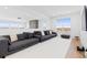 Spacious living room with a large gray sectional, white walls, and plenty of natural light from big windows at 7517 Copper Sky Ct, Castle Pines, CO 80108