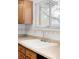 Close-up of kitchen sink beneath a window with natural light and wood cabinets at 11945 W 66Th Pl # A, Arvada, CO 80004