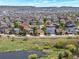 Aerial view of a residential neighborhood with houses, streets, and a pond in the foreground, under a bright sky at 2872 Dreamcatcher Loop, Castle Rock, CO 80109