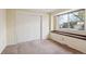 Bedroom featuring a sliding closet door, neutral carpeting and walls, and a window view of the outdoors at 14072 W Alaska Dr, Lakewood, CO 80228