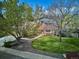Charming home with a well-manicured front yard, mature trees, and a welcoming pathway leading to the entrance at 14072 W Alaska Dr, Lakewood, CO 80228