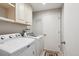 Bright laundry room featuring a washing machine, dryer, cabinets, and a door to another room at 14072 W Alaska Dr, Lakewood, CO 80228