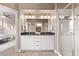 Modern bathroom features a double vanity with a glass-enclosed shower and a neutral color scheme at 1928 W 67Th Pl, Denver, CO 80221