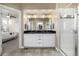 A bathroom boasts a dual sink vanity with granite countertop and glass enclosed shower at 1928 W 67Th Pl, Denver, CO 80221