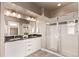 Modern bathroom features a double vanity with sleek white cabinets and a glass-enclosed shower at 1928 W 67Th Pl, Denver, CO 80221
