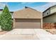Exterior view of a two car garage with a concrete driveway and a tree on the left at 1928 W 67Th Pl, Denver, CO 80221
