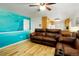 Inviting living room features a cozy brown leather sofa and unique underwater mural wall accent at 8595 S Yarrow St, Littleton, CO 80128