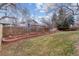 Large grassy backyard with a wooden fence, brick planter, and mature trees at 7484 E Mercer Pl, Denver, CO 80237