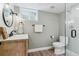 Stylish bathroom with a wood vanity, round mirror, and a glass-enclosed shower at 7484 E Mercer Pl, Denver, CO 80237