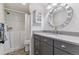 Modern bathroom features a walk-in tub, gray vanity, round mirror, and updated fixtures at 7484 E Mercer Pl, Denver, CO 80237