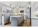 Modern kitchen with stainless steel appliances, white cabinets, island with seating, and natural light at 7484 E Mercer Pl, Denver, CO 80237