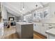 Bright kitchen with white cabinets, gray island, stainless sink, hardwood floor, pendant lights, and large window at 7484 E Mercer Pl, Denver, CO 80237