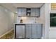 Charming kitchenette with gray cabinets, stainless steel mini-fridge, sink, and mosaic tile backsplash at 7484 E Mercer Pl, Denver, CO 80237