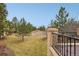 View of a spacious backyard with mature trees and landscaping, seen from a patio with black metal railing at 5035 Vermillion Dr, Castle Rock, CO 80108