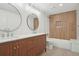 Modern bathroom with wood vanity, gold fixtures, double sinks, tub, and designer mirrors at 5035 Vermillion Dr, Castle Rock, CO 80108