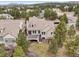 Aerial view of the home's backyard featuring a wooden deck, stairs, lawn, and mature trees at 5035 Vermillion Dr, Castle Rock, CO 80108