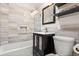 Modern bathroom with gray tiled walls, glass shower doors, and a dark vanity with storage at 11224 W 28Th Pl, Lakewood, CO 80215