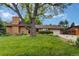 Well-kept front yard with a lush green lawn, mature trees, colorful flowerbeds, and a brick home, offering a welcoming curb appeal at 11224 W 28Th Pl, Lakewood, CO 80215