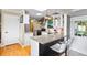 Bright, open kitchen featuring an island with seating, white cabinets, stainless steel appliances, and hardwood floors at 11224 W 28Th Pl, Lakewood, CO 80215