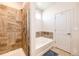 Bright bathroom with a walk in shower and separate bathtub, a tiled wall and a blue rug at 56459 E 23Rd Pl, Strasburg, CO 80136
