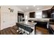 Modern kitchen featuring dark wood cabinetry, granite countertops, and a center island with bar seating at 56459 E 23Rd Pl, Strasburg, CO 80136