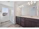 Bathroom featuring double vanity, quartz countertops, framed mirror, and tiled walk-in shower at 1311 Rock Cliff Ave, Erie, CO 80516