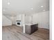 Open-concept kitchen and living area with light wood flooring, a fireplace, and plenty of natural light at 1311 Rock Cliff Ave, Erie, CO 80516