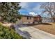 Tan brick home with an inviting driveway, complemented by mature trees for added charm at 2700 W 91St Ave, Denver, CO 80260