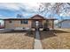A tan brick home featuring a walkway to the front door, creating an inviting entrance at 2700 W 91St Ave, Denver, CO 80260