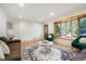 Cozy living room featuring hardwood floors, ample natural light from a bay window, and comfortable seating at 2840 S Yates St, Denver, CO 80236