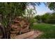Backyard water feature with greenery, brick pavers, and grass at 2840 S Yates St, Denver, CO 80236