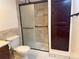 A well lit bathroom with a wooden cabinet, sliding glass shower doors and a toilet at 390 Zang St # 5-102, Lakewood, CO 80228