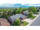 An aerial view of a single Gathering home surrounded by mature trees with mountain views in the distance at 8696 W Iliff Ave, Lakewood, CO 80227