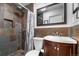 Stylish bathroom featuring stone-style tile in the shower, dark wood vanity with white sink, and chrome fixtures at 2381 Newark St, Aurora, CO 80010