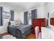 Bright bedroom features hardwood floors, two windows with gray curtains, and a red dresser with a white desk at 2381 Newark St, Aurora, CO 80010