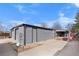 View of the detached garage as well as the covered patio area and outdoor fire pit in the backyard at 2381 Newark St, Aurora, CO 80010