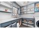 Well-organized laundry room featuring open shelves, baskets, and a sink with blue cabinetry and white countertops at 2381 Newark St, Aurora, CO 80010