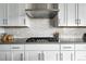 Modern kitchen with white cabinets, stainless steel range hood, and subway tile backsplash at 4855 Saddle Iron Rd, Castle Rock, CO 80104