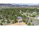 An aerial view of the property nestled among mature trees with other houses in the distance at 3640 Summertime Ct, Monument, CO 80132