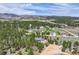 An aerial view of the property nestled among mature trees with other houses in the distance at 3640 Summertime Ct, Monument, CO 80132